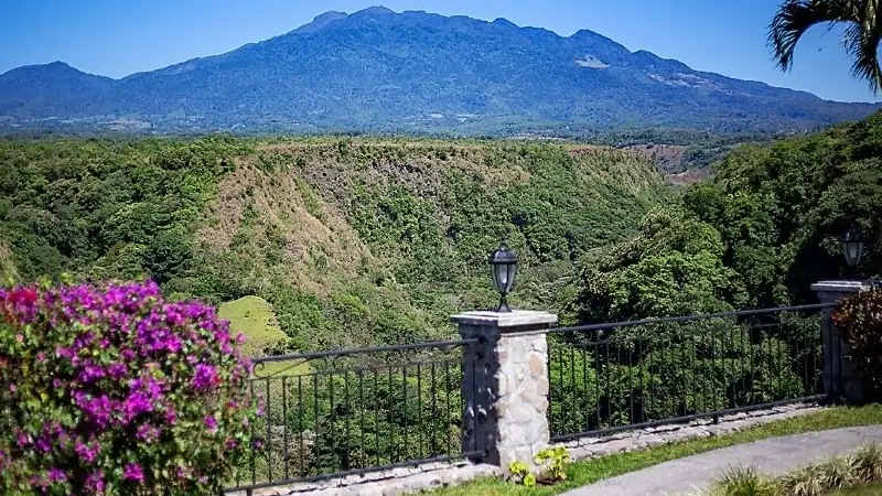 Lush canyon and mountain landscape in Boquete with tropical greenery, flowering plants, and clear blue skies.
