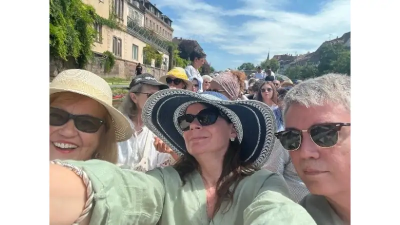 Kathleen and Lief enjoying a sunny boat tour, taking a selfie while cruising along a scenic canal with fellow travelers.