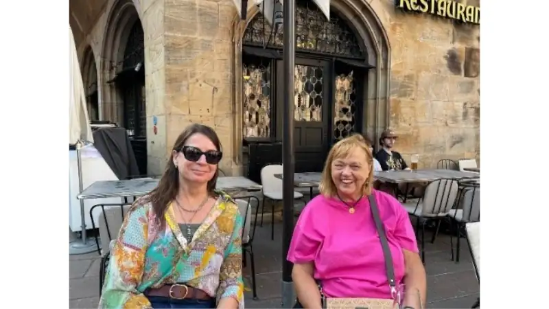 Kathleen and a companion sitting at an outdoor café in Strasbourg's historic center, enjoying a sunny day.