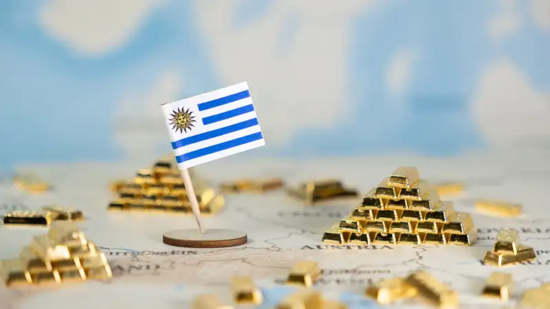 Miniature Uruguay flag stands proudly surrounded by golden bars on a global map