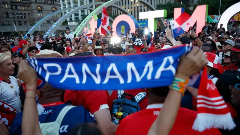 Panama soccer fans gather in downtown Toronto, waving flags and holding a Panama scarf while celebrating during an international football tournament event.