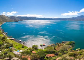 Panoramic view of the beautiful lake of Coatepeque in El Salvador, with a blue sky, in the season where its waters are turquoise and most of its mountains and vegetation are green.