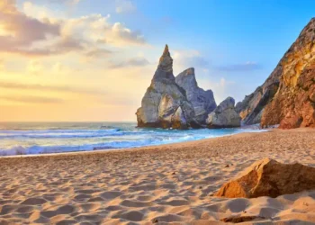 Portugal Ursa Beach at atlantic coast of Atlantic Ocean with rocks and sunset sun waves and foam at sand of coastline picturesque landscape panorama.