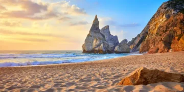 Portugal Ursa Beach at atlantic coast of Atlantic Ocean with rocks and sunset sun waves and foam at sand of coastline picturesque landscape panorama.