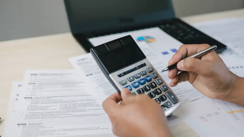 Professional calculating tax using a calculator, representing fringe benefit taxation