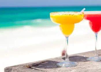 two perfect mango and strawberry margarita, beach background