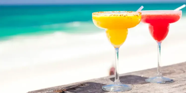 two perfect mango and strawberry margarita, beach background
