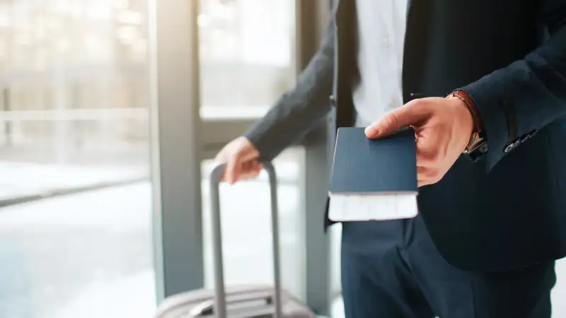 Man in a suit standing at an airport window, symbolizing travel or moving