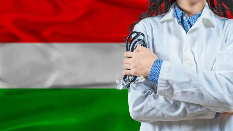 Healthcare professional standing in front of a Hungarian flag, symbolizing medical care