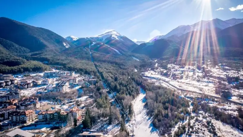 Snow-covered Bulgarian mountain landscape with a resort town surrounded by forests.