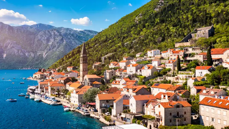 View of the historic town of Perast at famous Bay of Kotor on a beautiful sunny day with blue sky and clouds in summer, Montenegro. Historic city of Perast at Bay of Kotor in summer, Montenegro.