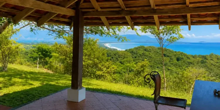 Rustic open-air terrace overlooking the lush coastline and turquoise waters of Los Islotes, Panama, with mountains and tropical forest stretching into the distance.