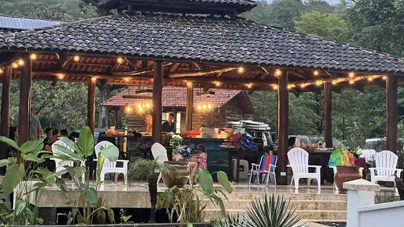 A covered outdoor pavilion with warm lighting, seating, and a relaxing ranch atmosphere.