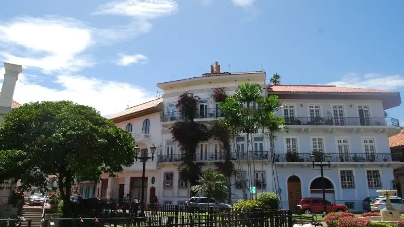 Elegant colonial architecture in Panama, showcasing a beautifully preserved white building, ornate balconies, tropical greenery, and a bright Caribbean sky.