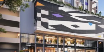 Modern mixed-use building with vibrant street-level retail, including a market, coffee shop, and laundry, featuring a bold geometric mural across the facade.