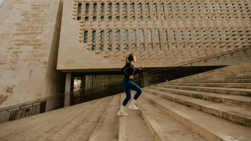 Woman exercises on steps of building in Malta while doing cardio workout