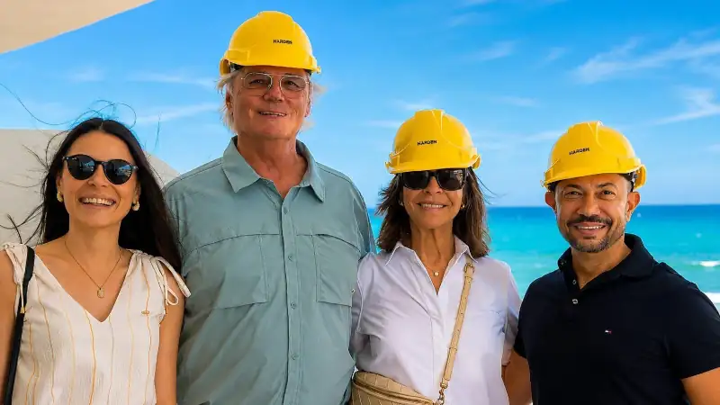 Team members wearing safety helmets during a beachfront project site visit, posing with the ocean in the background.