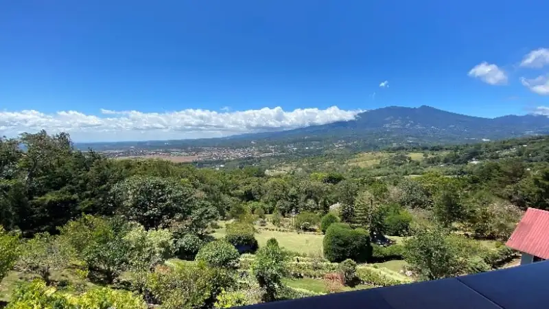 Panoramic view of Boquete’s lush valley and surrounding mountains beneath a bright blue sky.
