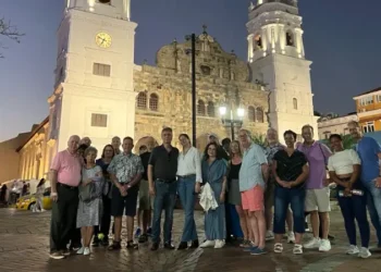 Group posing in front of a historic twin-towered church in Casco Viejo at dusk, with illuminated architecture and lively streets in the background.