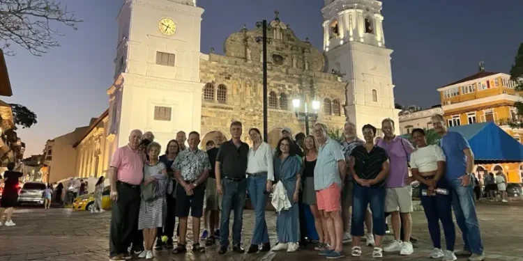 Group posing in front of a historic twin-towered church in Casco Viejo at dusk, with illuminated architecture and lively streets in the background.