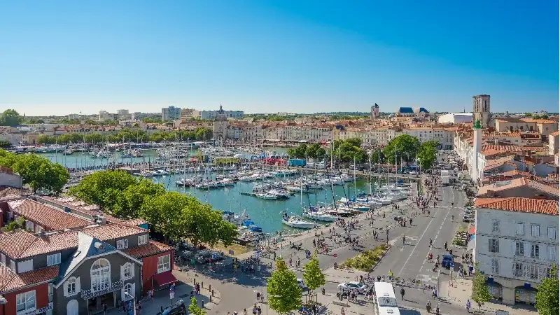 Panoramic view of La Rochelle’s Old Port, featuring a marina filled with sailboats, historic buildings, and a lively waterfront.