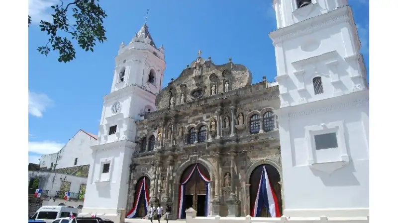 Historic cathedral façade in Casco Viejo decorated with Panamanian flags.