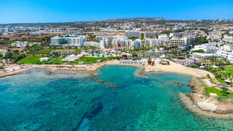 Aerial bird's eye view Pernera beach Protaras, Paralimni, Famagusta, Cyprus. The tourist attraction golden sand bay with sunbeds, water sports, hotels, restaurants, people swimming in sea from above