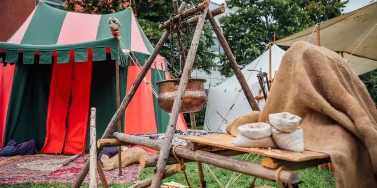 Medieval Festival Camp Scene With Colorful Tent Open Fire Pit And Wooden Table Setup Historical Reenactment Outdoor Living Exhibit