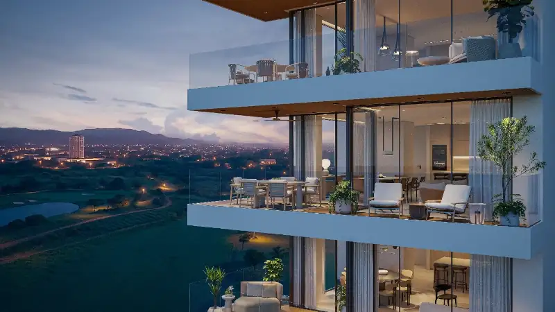 Beautiful golf course landscape with manicured fairways, sand bunkers, a tranquil water feature, and striking high-rise residences against a mountain backdrop.