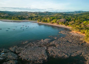 Aerial view of rocky coastline and turquoise waters in Santa Catalina, one of the premier Panama beach towns, with boats and lush tropical forest.