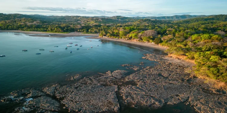 Aerial view of rocky coastline and turquoise waters in Santa Catalina, one of the premier Panama beach towns, with boats and lush tropical forest.