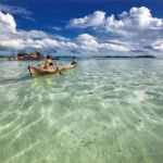 Wooden boats rowing away from an Indonesian beach. indonesia gallery