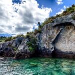 A cliff next to the ocean with a moari carving on the side