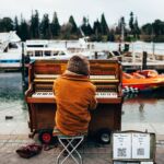 Bundled up man playing piano outside on the docs