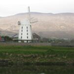 An old windmill turns on the river edge in Ireland.