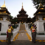 Thai women in traditional dress flank the steps to a Buddhist temple, Thailand.