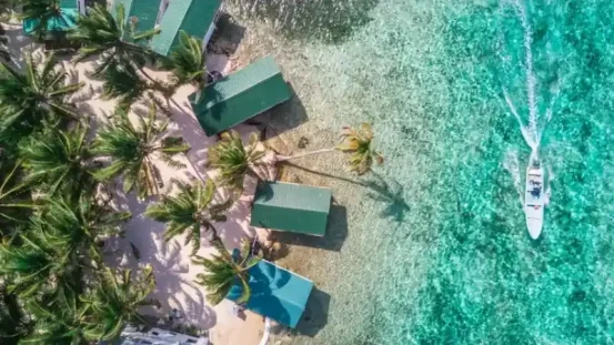 Aerial drone view of Tobacco Caye small Caribbean island with palm trees and bungalows in the Belize Barrier Reef AdobeStock/Duarte
