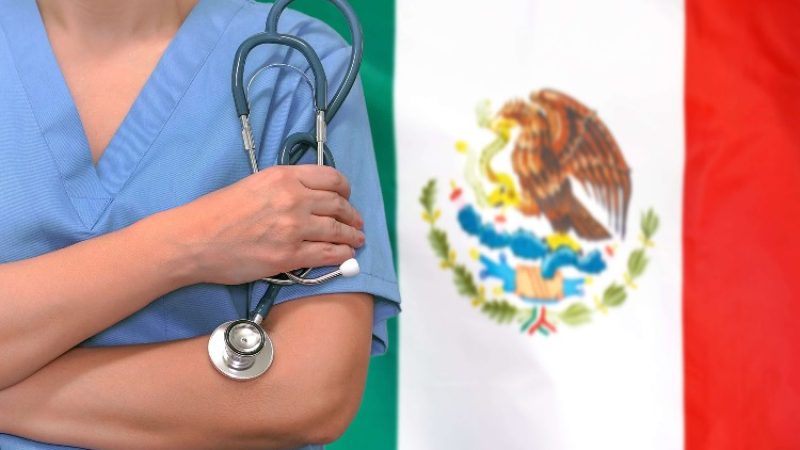 Female doctor with stethoscope in hand with the Mexican flag as background.
