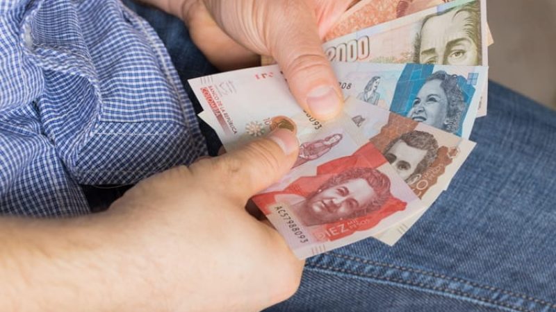 A man holding a bundle of Colombian pesos in his hands