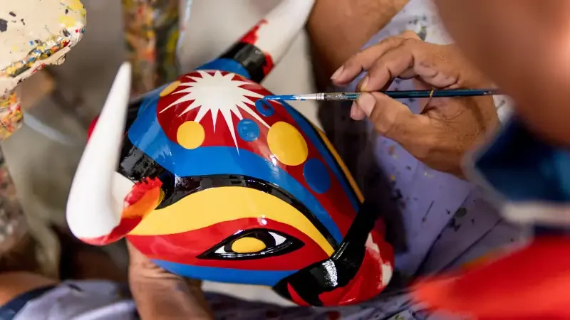 hands painting bull mask carved in wood and painted with commemorative colors of the carnival of barranquilla colombia