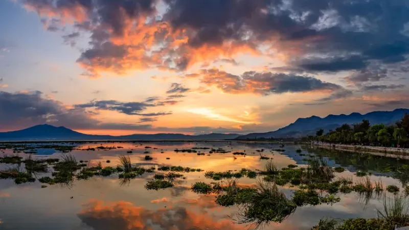 Orange and red sunset with misty mountains behind lake Chapala and the malecon on the right. mexico ajijic